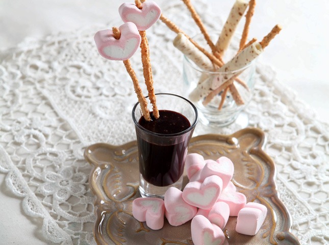 cocoa orange dip in a shotglass, on a plate with heart marshmallows