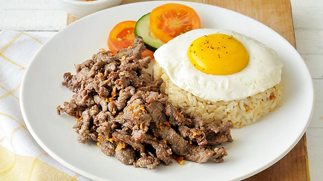 tapsilog with beef tapa, fried rice, and fried egg on a white plate