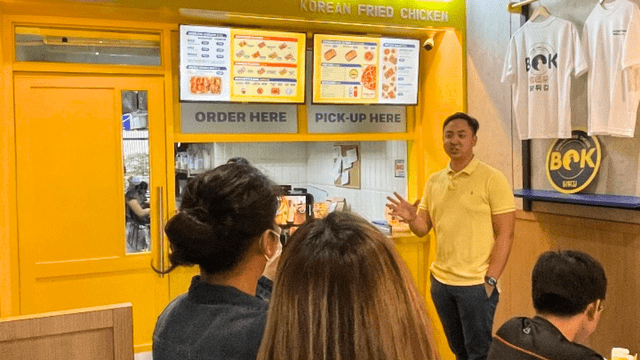 Bok Korean Fried Chicken owner talking in front of a Bok branch