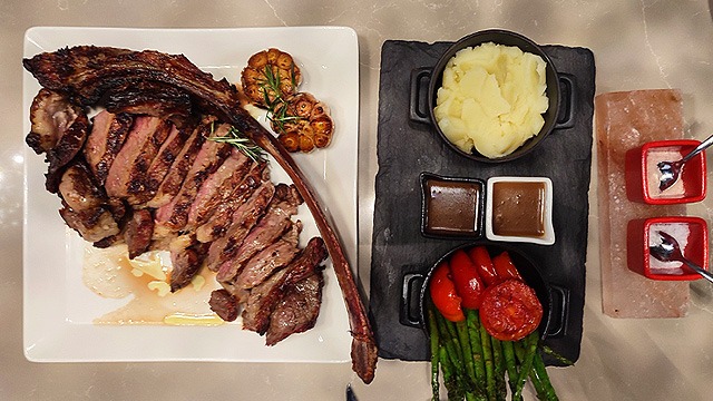 tomahawk steak with grilled side dishes, sauces, and salts from il primo steakhouse in nustar cebu