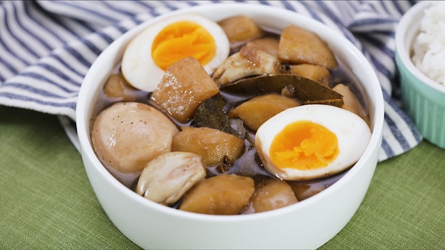 filipino adobo with hard boiled egg (itlog) and potatoes (patatas) in a white bowl