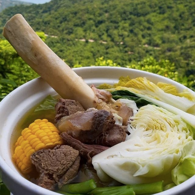 bowl of bulalo with mountain view in the background