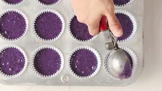 ube cupcake batter poured into cupcake liners in cupcake tin by an ice cream scoop 