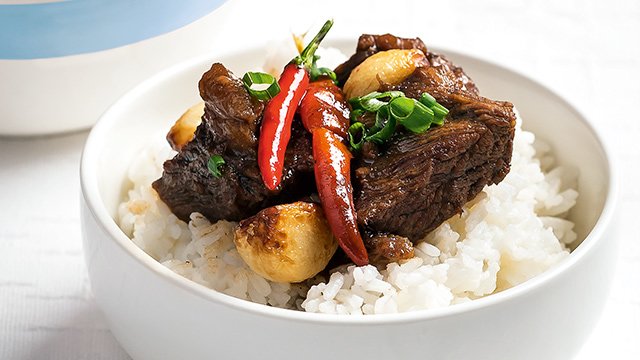 spicy beef adobo in a bowl topping rice