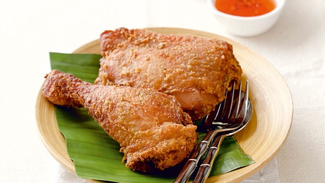 Gai tod or thai fried chicken, legs and thai on a yellow plate lined with a banana leaf